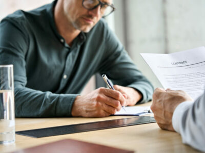 Businessman signing partnership contract at meeting with partner or lawyer.
