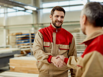 Happy male workers greeting at carpentry workshop.